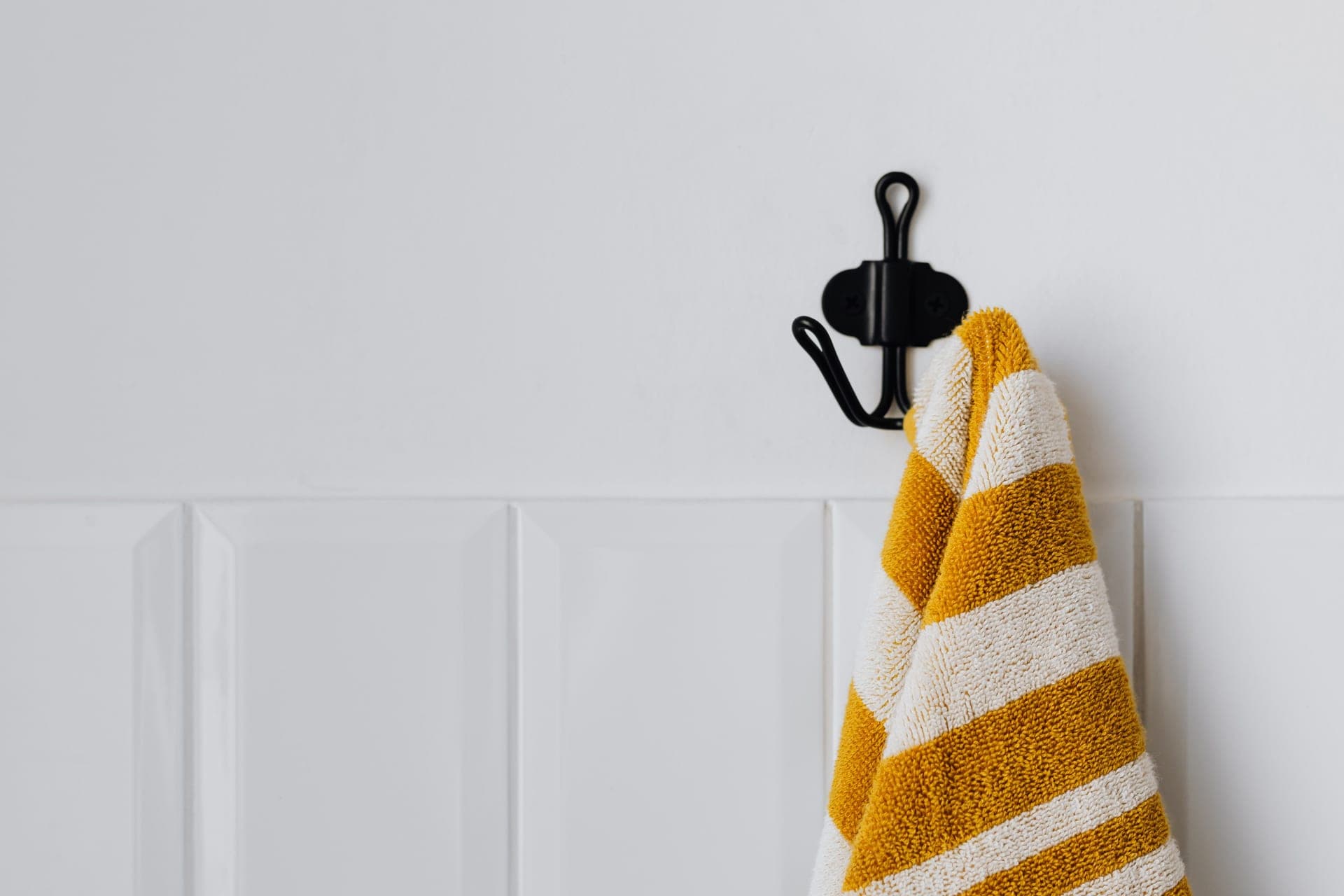 A white adhesive hook mounted on a plain painted interior wall