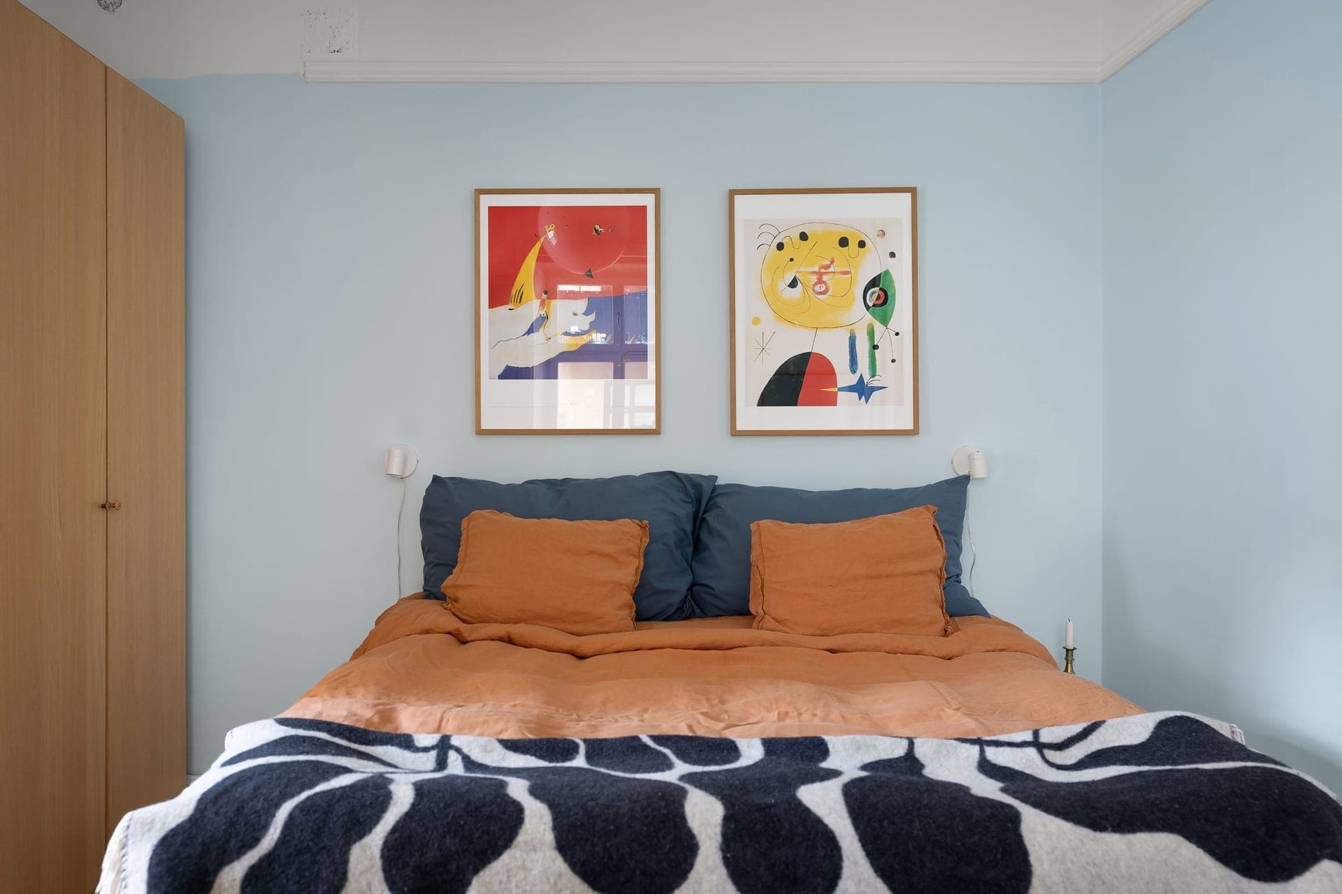 A framed print above a bed with a neutral headboard