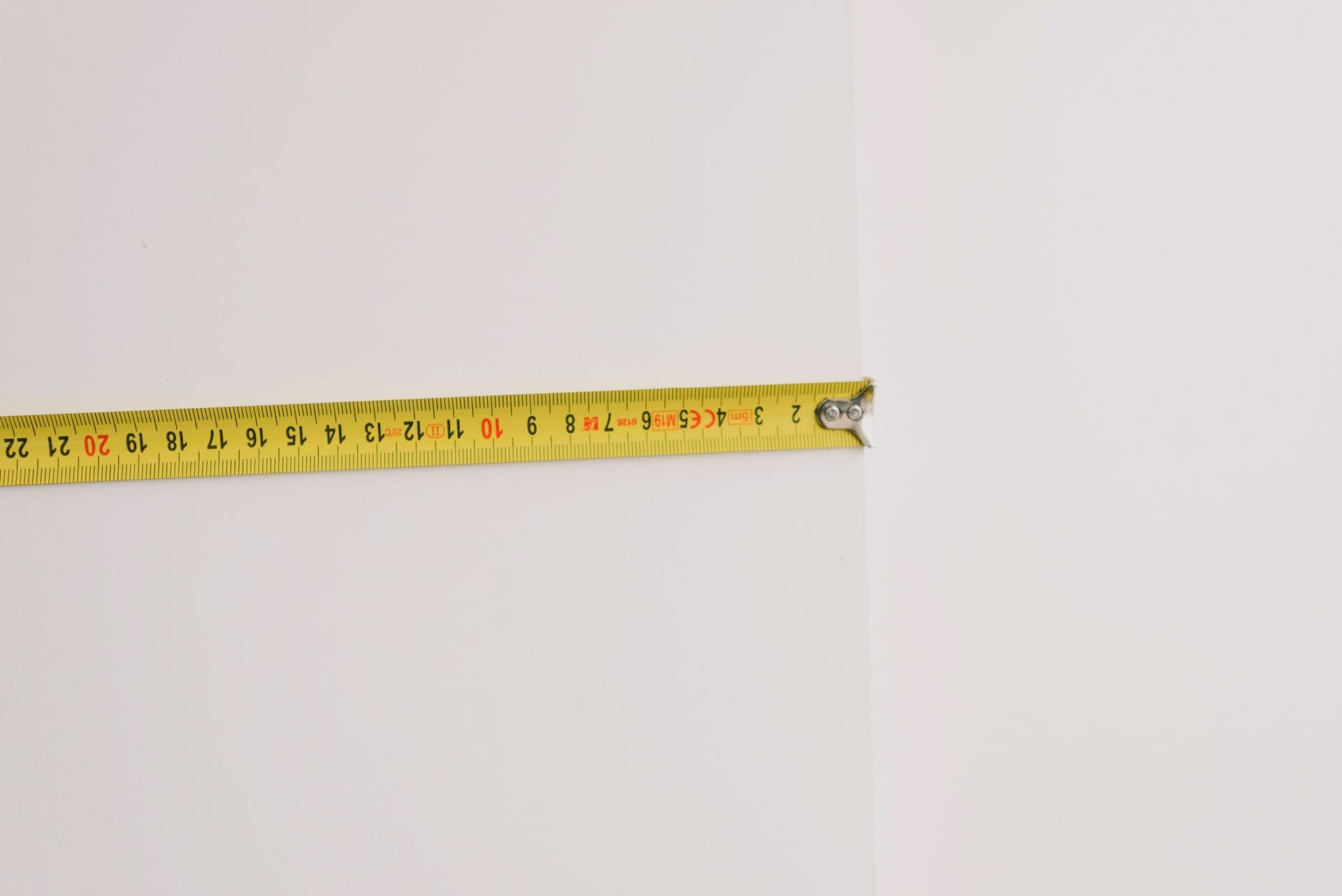 A tape measure held against a wall beside a framed print