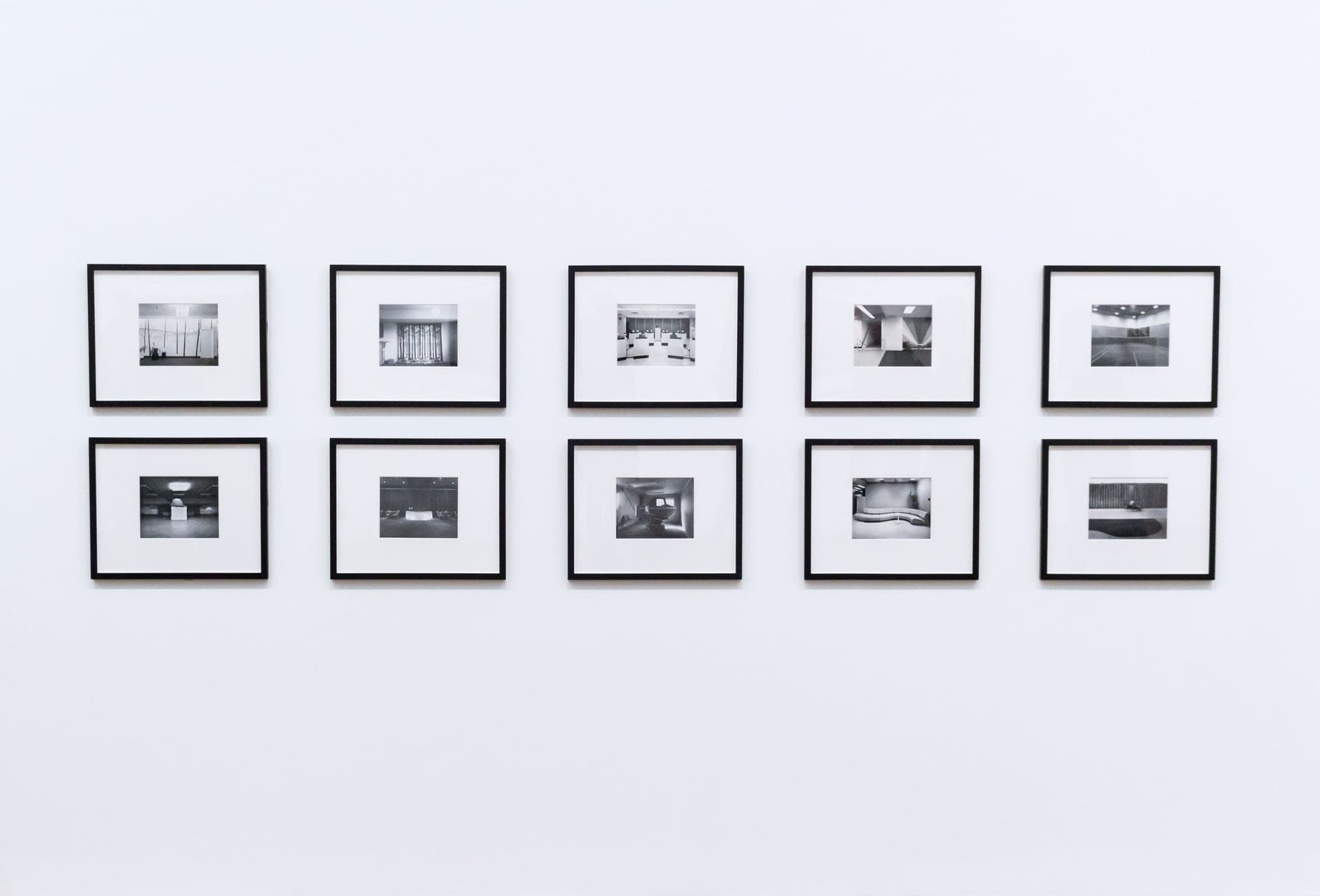 A wall of framed prints in several different frame finishes