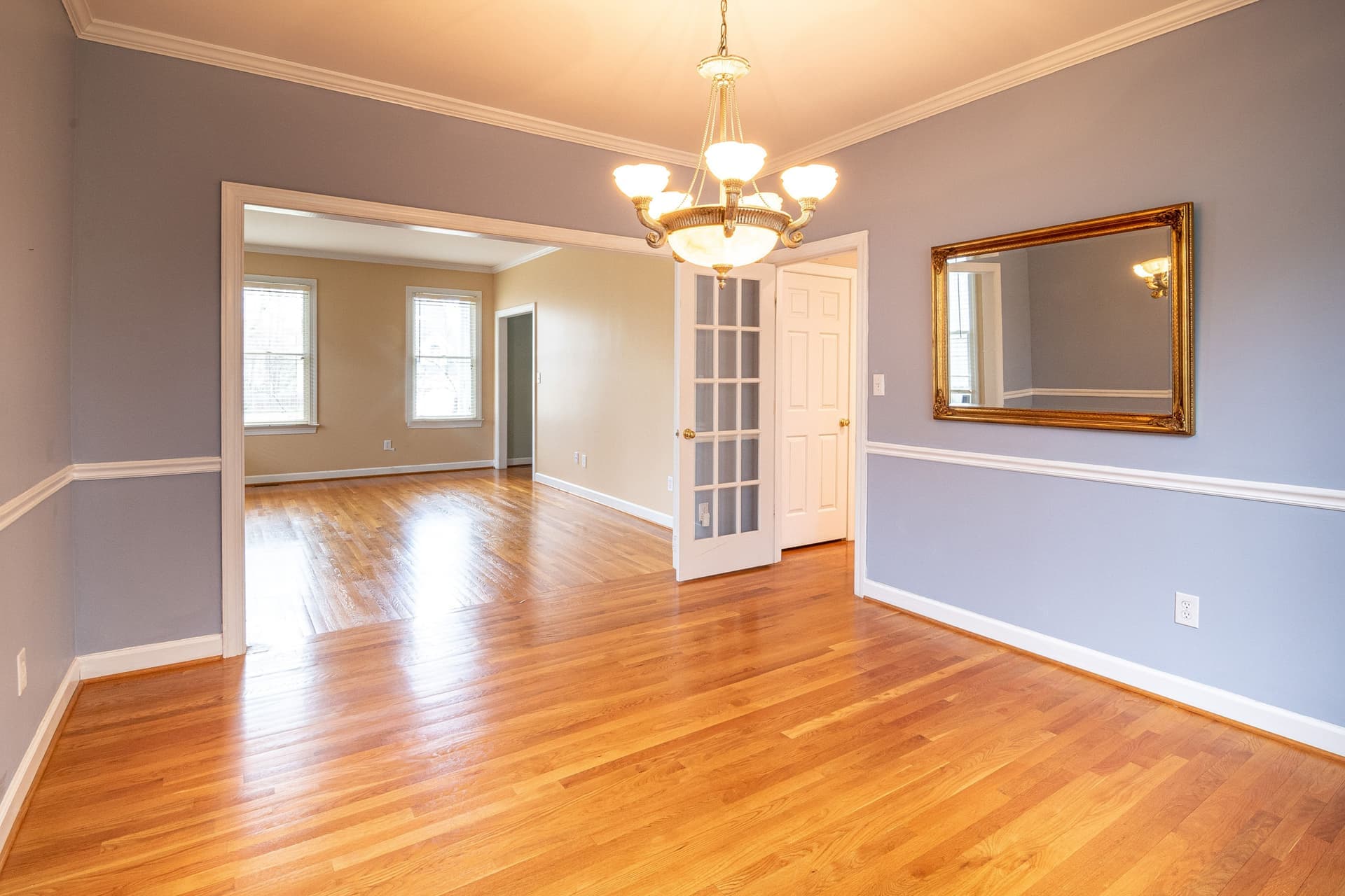 A slim picture rail mounted near the ceiling with frames hanging from cords