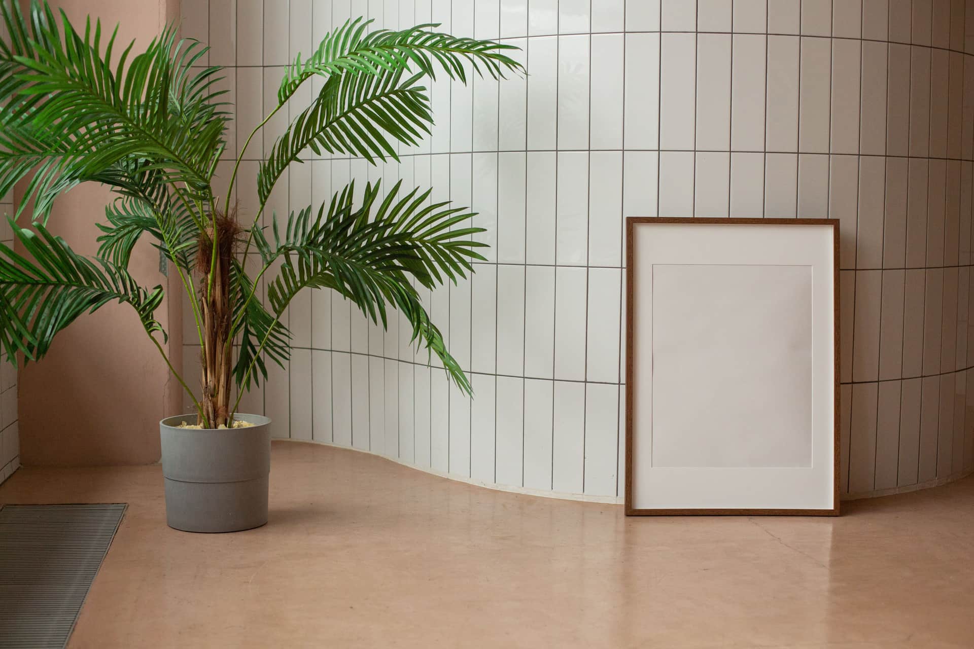 A large black poster frame on a plain wall in a bright room