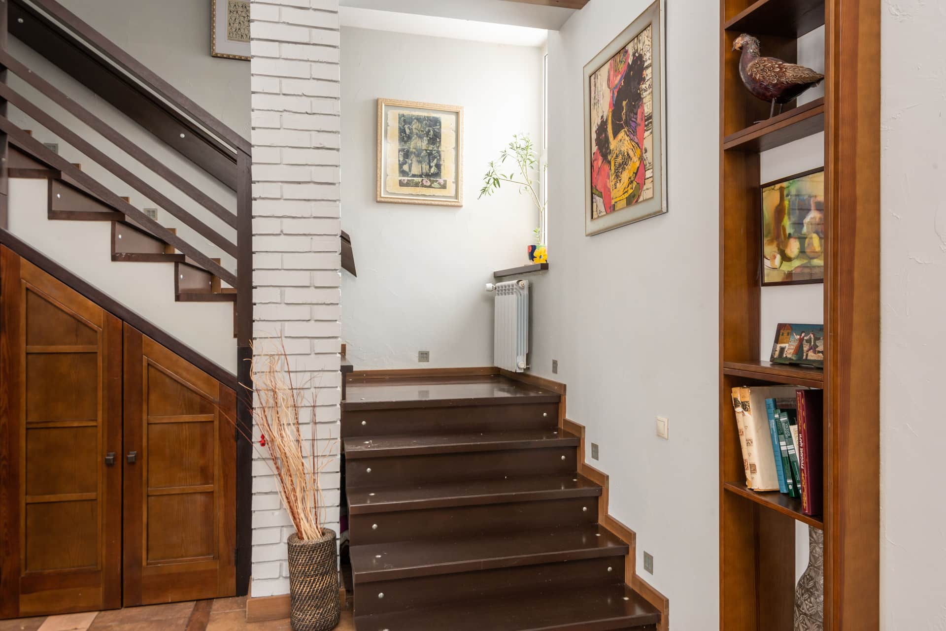 Framed pictures climbing a staircase wall beside a handrail