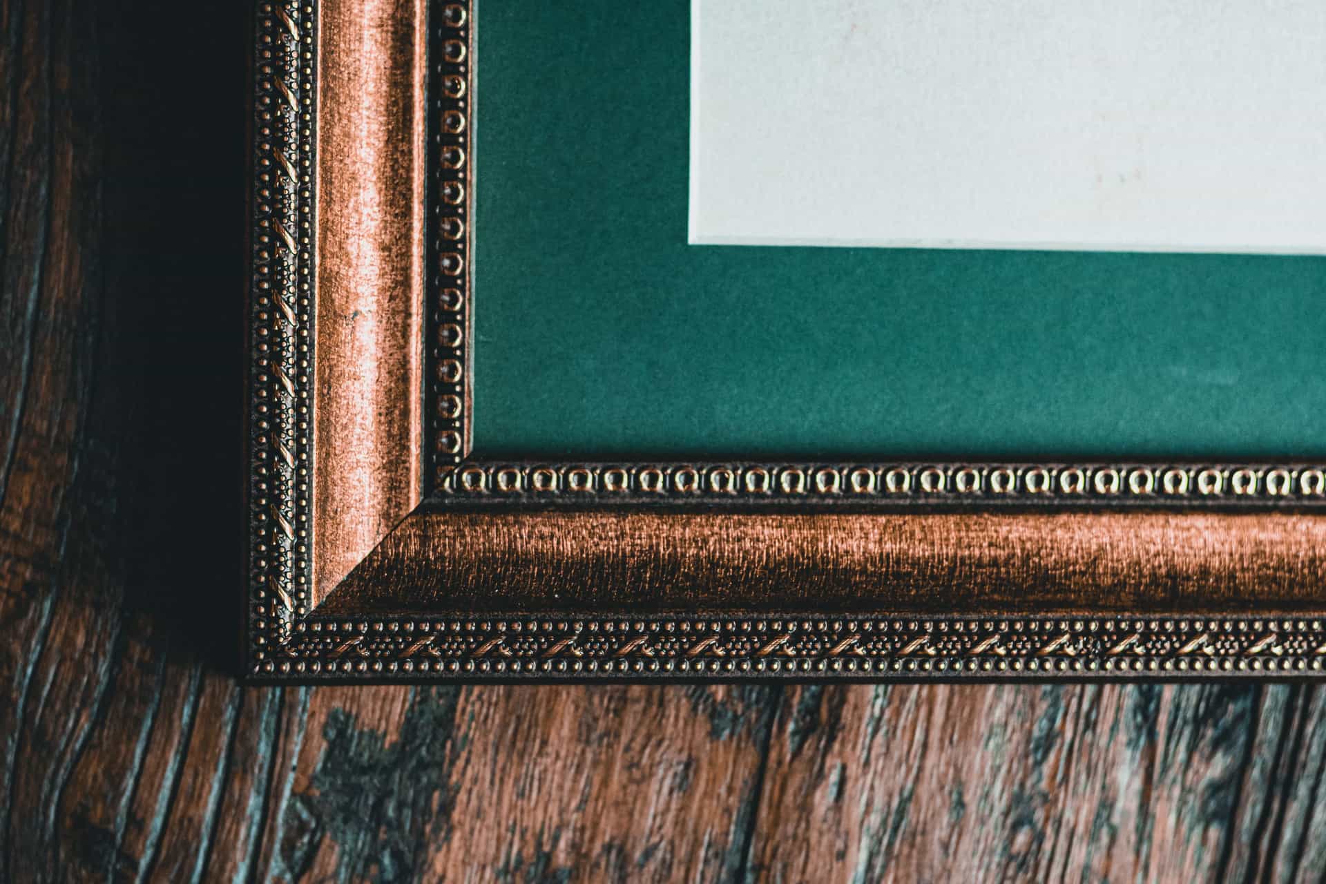 Wooden and metal picture frames side by side against a wall
