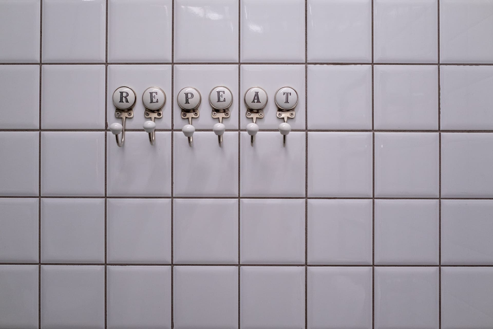 A small white adhesive wall hook mounted on a plain painted wall