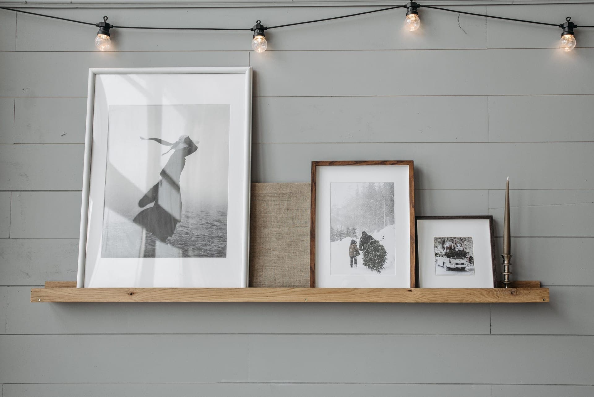 Framed prints leaning on a narrow wooden picture ledge above a sofa